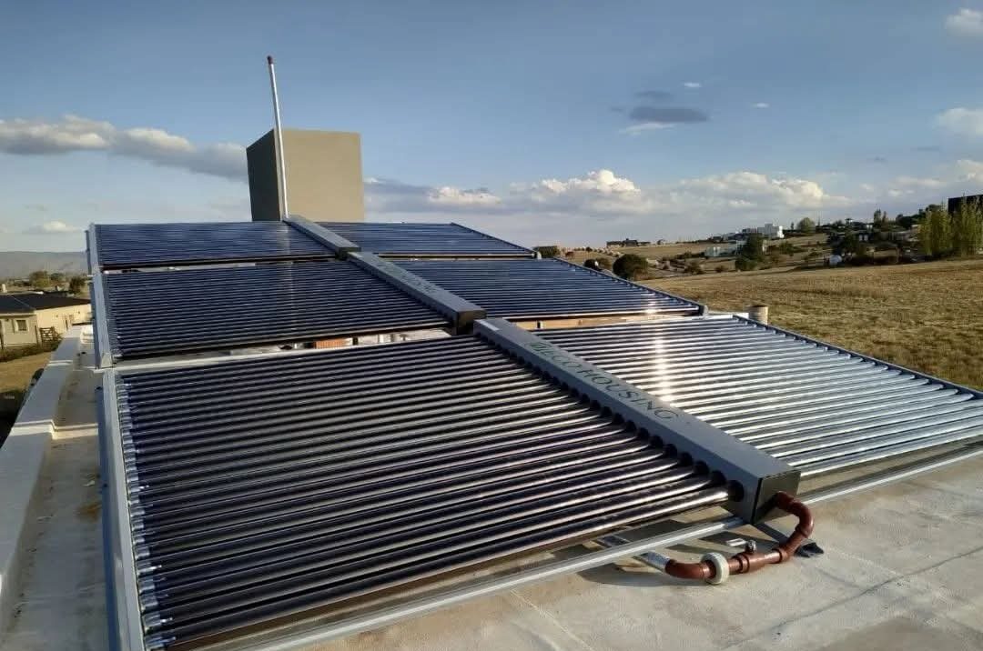 Colectores solares de tubos al vacío montados sobre cubierta para calefacción por piso radiante y climatización de piscina.